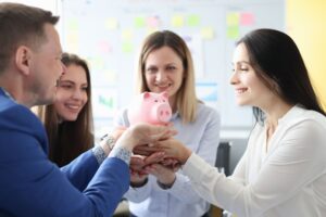 Equipe segurando cofrinho, representando o planejamento estratégico para economias com terceirização.